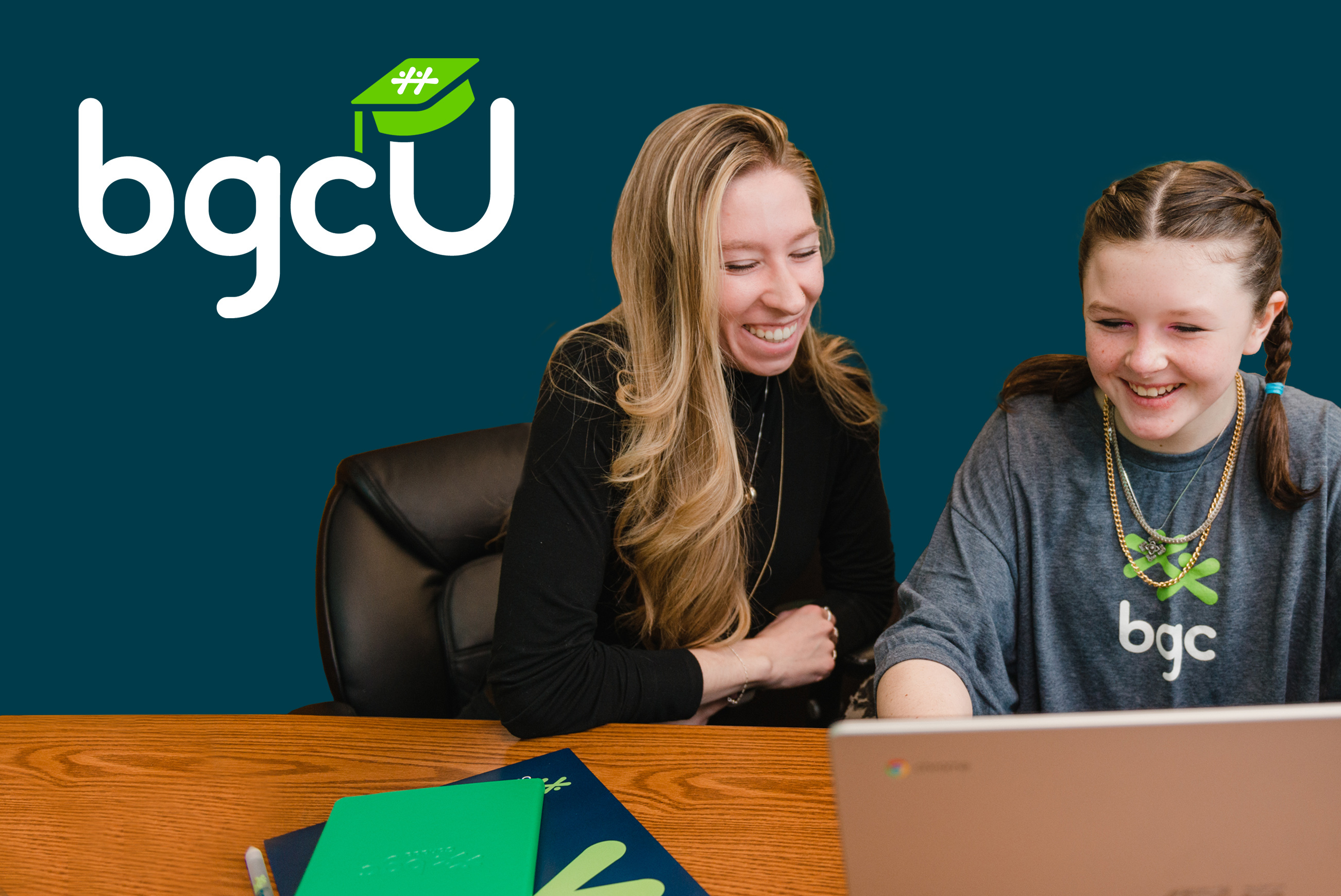 A smiling adult staff leader looks at a laptop screen with a smiling BGC youth member.