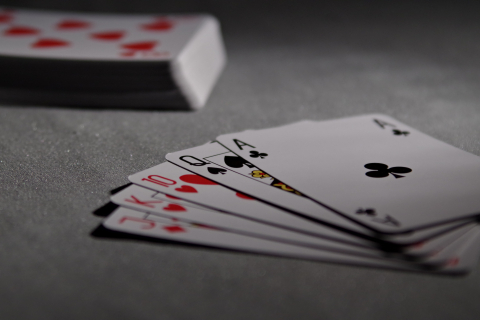 A hand of cards laid out on a table with a deck of cards in the background.