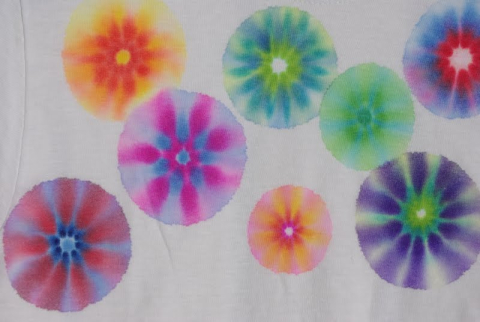 a white t-shirt with several patches of colorful tie-dye across the front. 