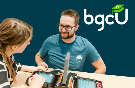 Two people playing a table game with the BGCU logo in the right top corner